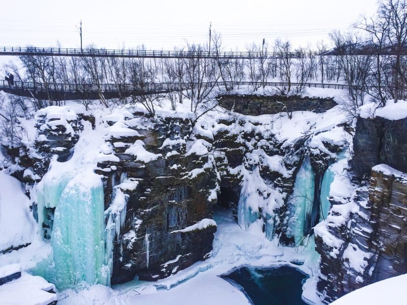 barren trees and frozen ice blue waterfalls in Abisko National Park