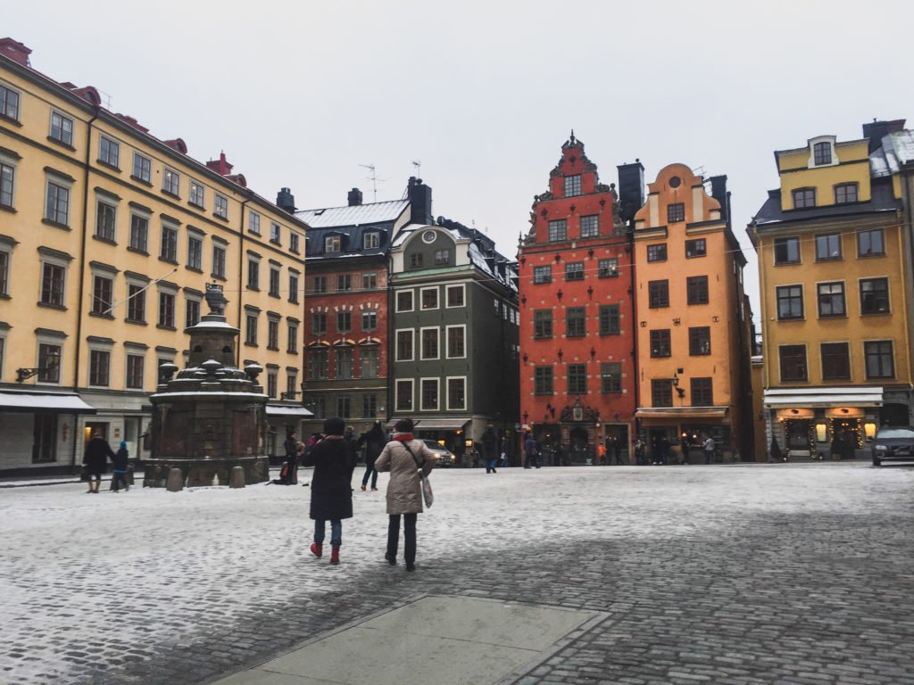 Stockholm's old town district of Gamla Stan in winter with white snow on the cobblestone ground with red and green and orange buildings from the medieval times