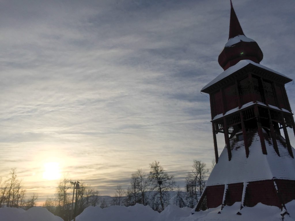 kiruna church in sweden with snowdrifts piling up atop a wooden church steeple