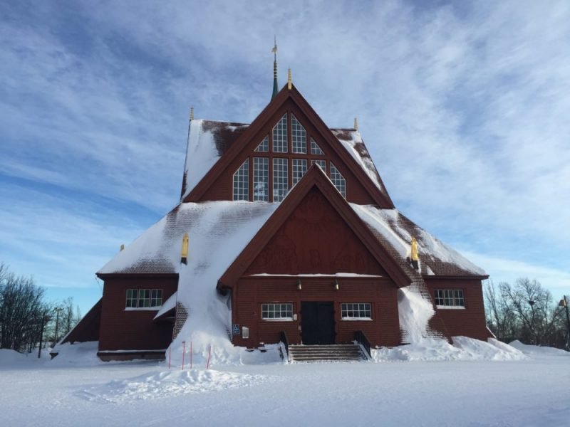 Kiruna Church Sweden covered in snow, evoking a real Arctic vibe, with a reddish-brown church and snow