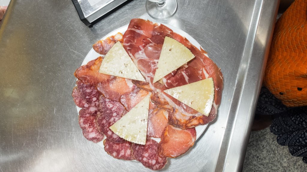 a plate of different kinds of ham and cured meat and cheese at the museo del jamon in madrid spain