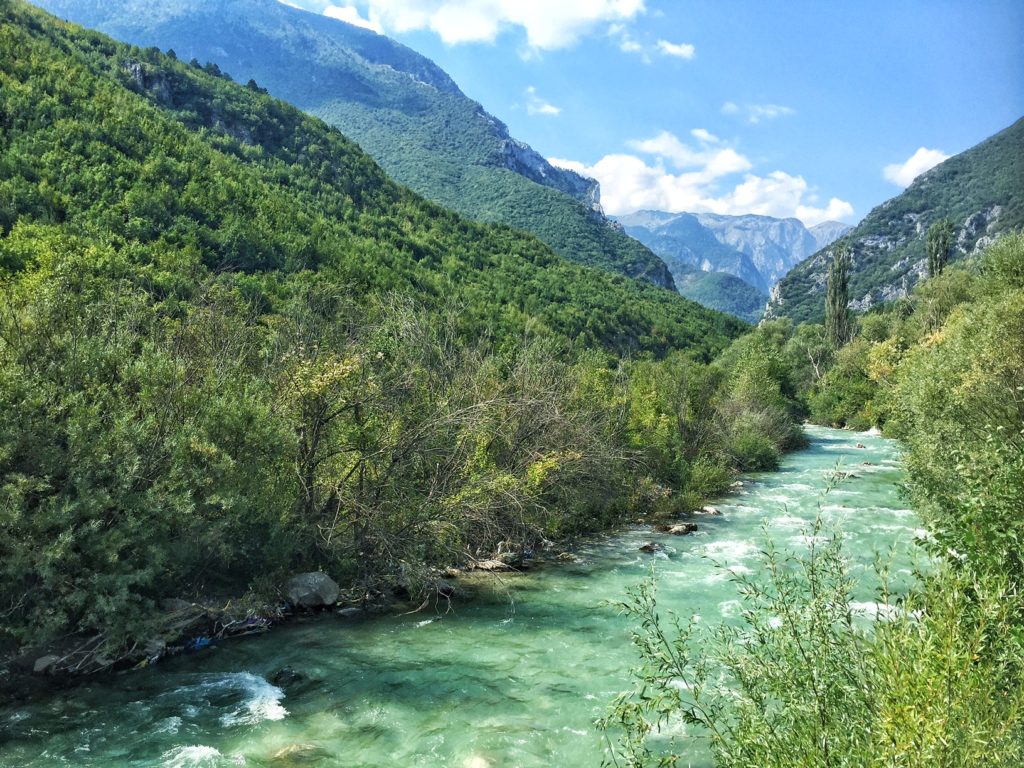 foothills of the mountains in kosovo with a clear river running through them