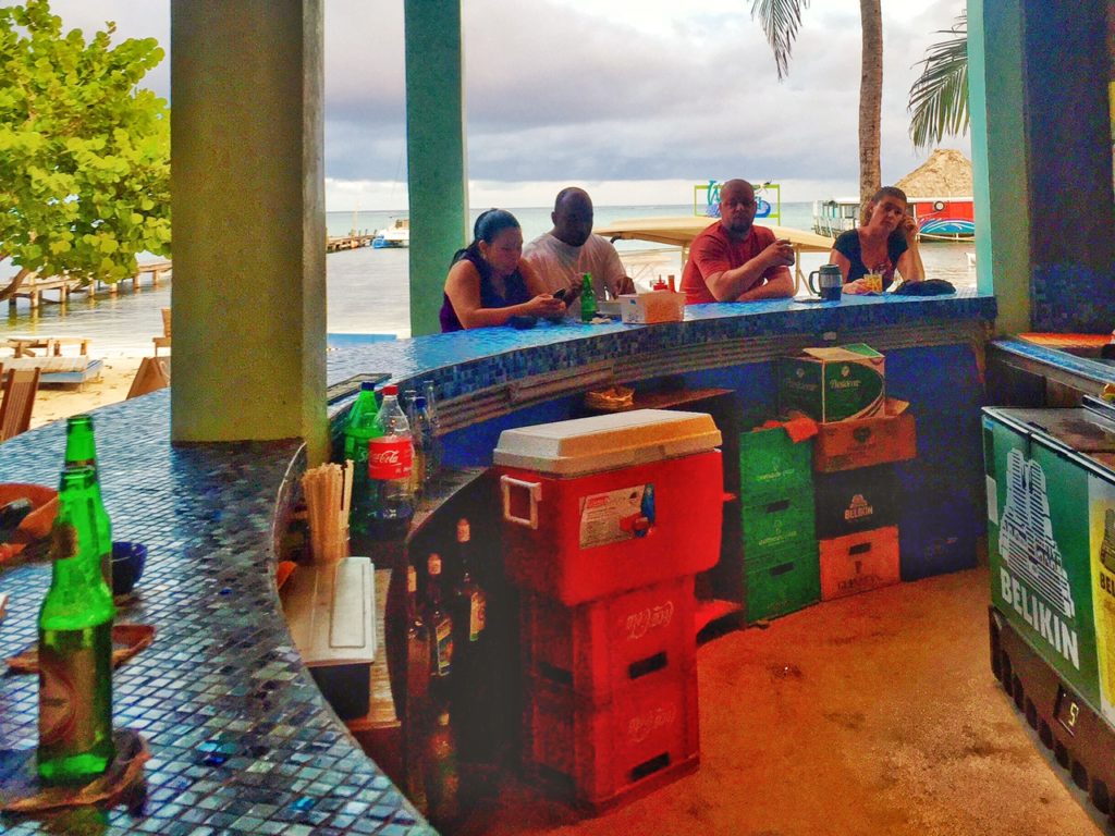 a colorful bar area with a mosaic tile counter and people sitting at the bar with the beach in the distance