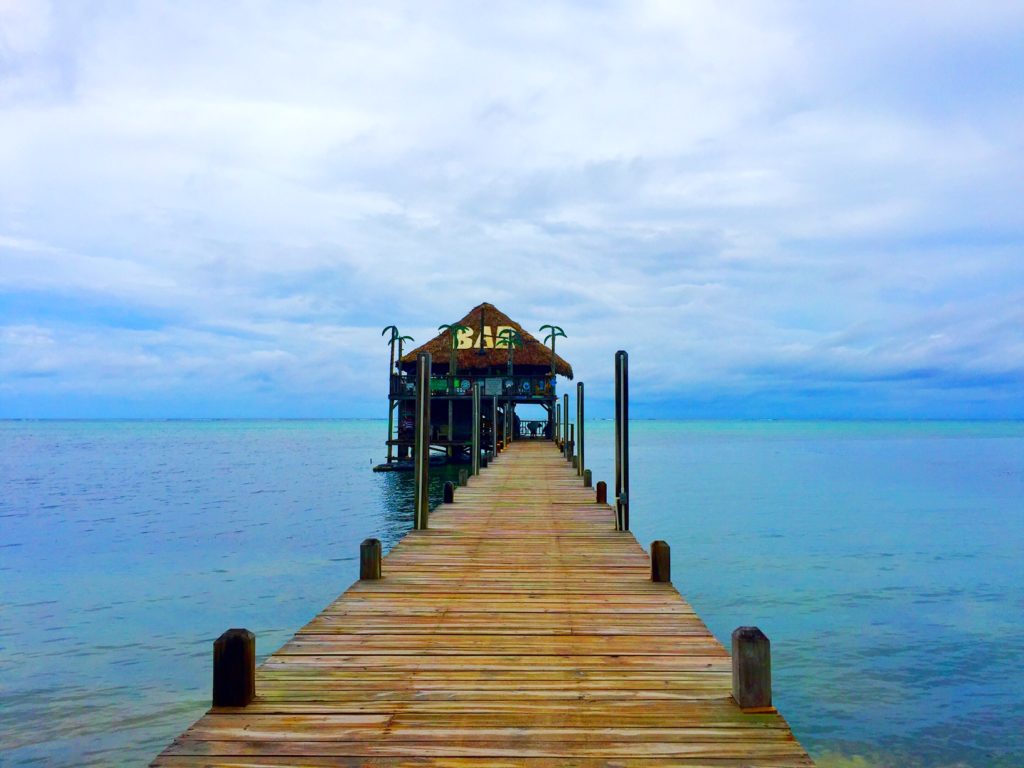 The palapa bar on a cloudy day in belize with a bar out on the pier