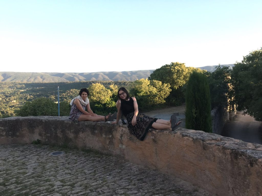 Allison Green and her friend sitting on a wall in Provence looking at the views at sunset