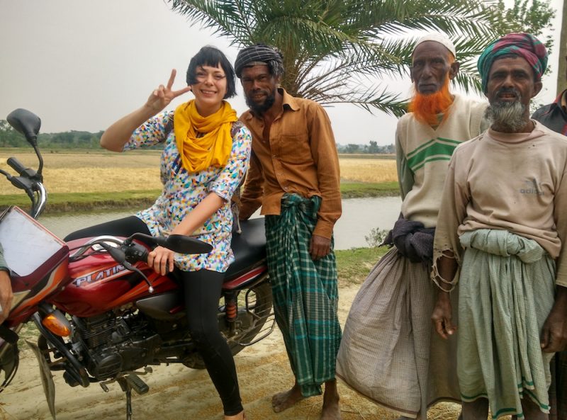 Alice on a motorbike with people in Bangladesh also posing with her