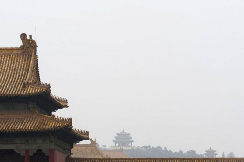 View of the rooftops of the Forbidden city in China with foggy sky and other pagodas visible