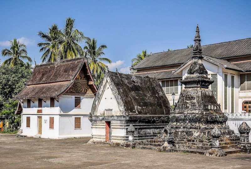 A view of a temple in Laos with stone carvings and white buildings