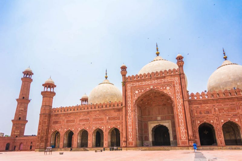 A pinkish red mosque in Pakistan with minarets and arches and domes