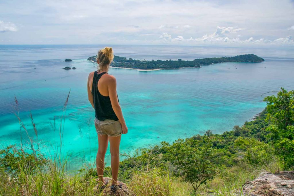 Blond woman in shorts in front of a blue sea in Thailand