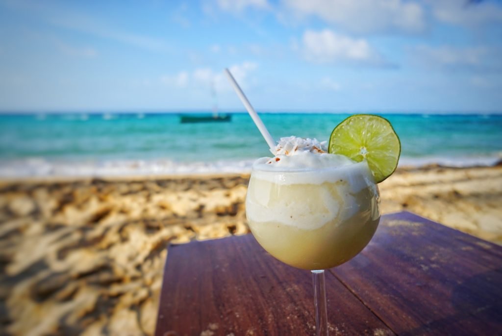 a pina colada on the beach with a lime and view of the ocean