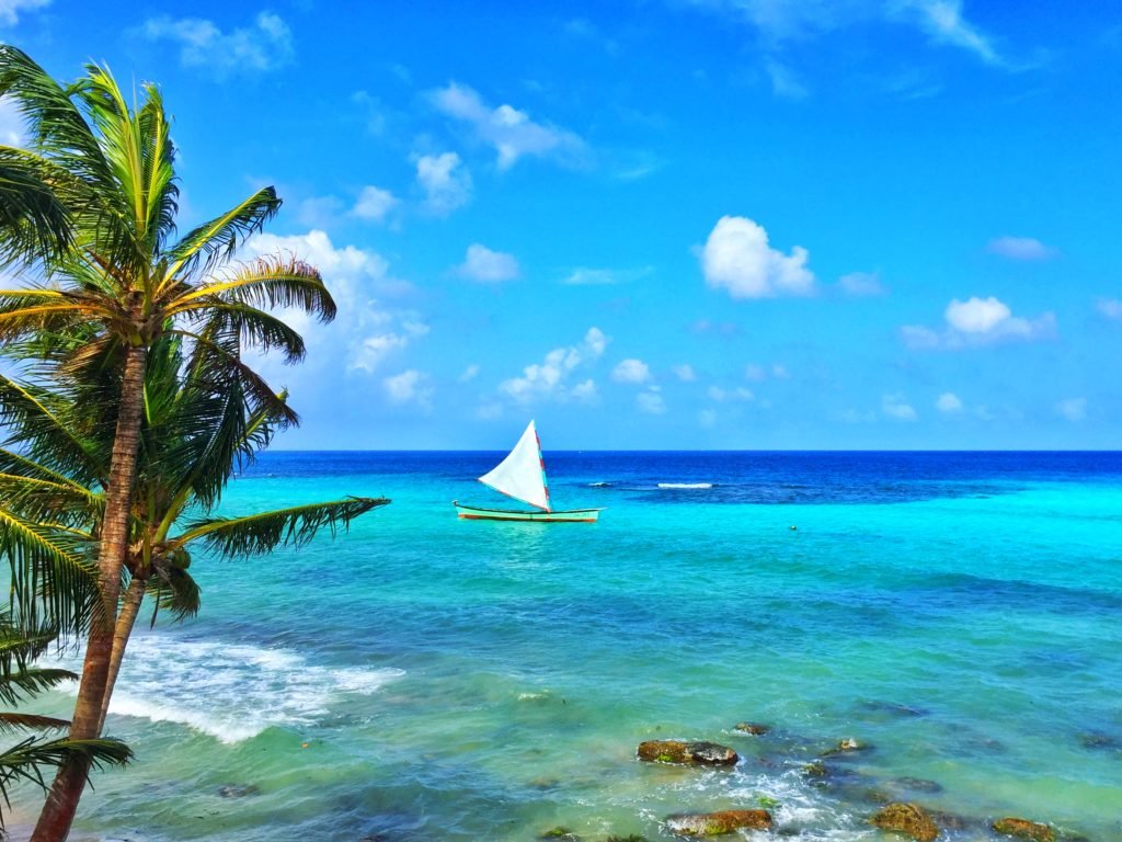 The pristine waters of Little Corn, one of my favorite places in Nicaragua, with a sailboat out on the turquoise and dark blue sea.