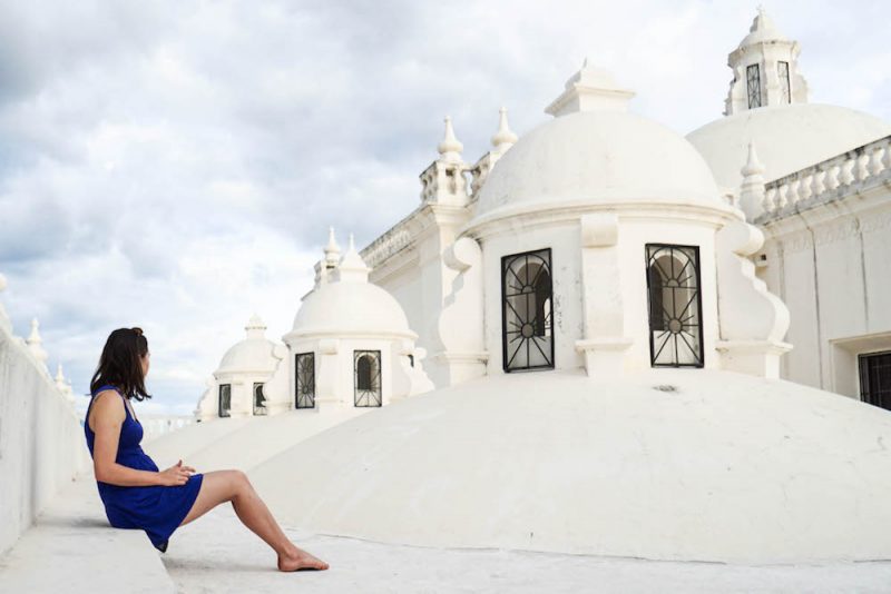 Allison Green wearing a blue dress sitting on top of a white cathedral in leon
