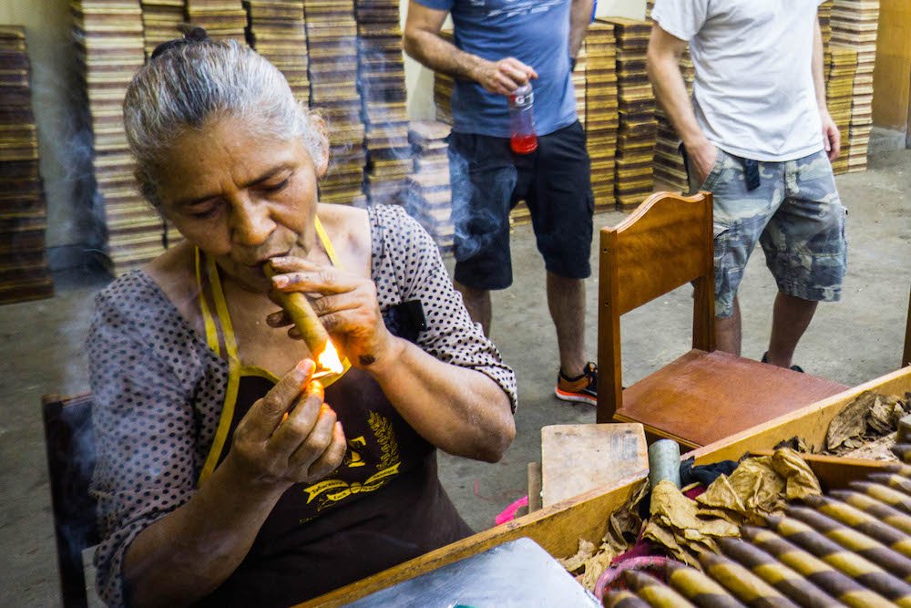 an older woman smoking a cigar at a nicaragua cigar factory