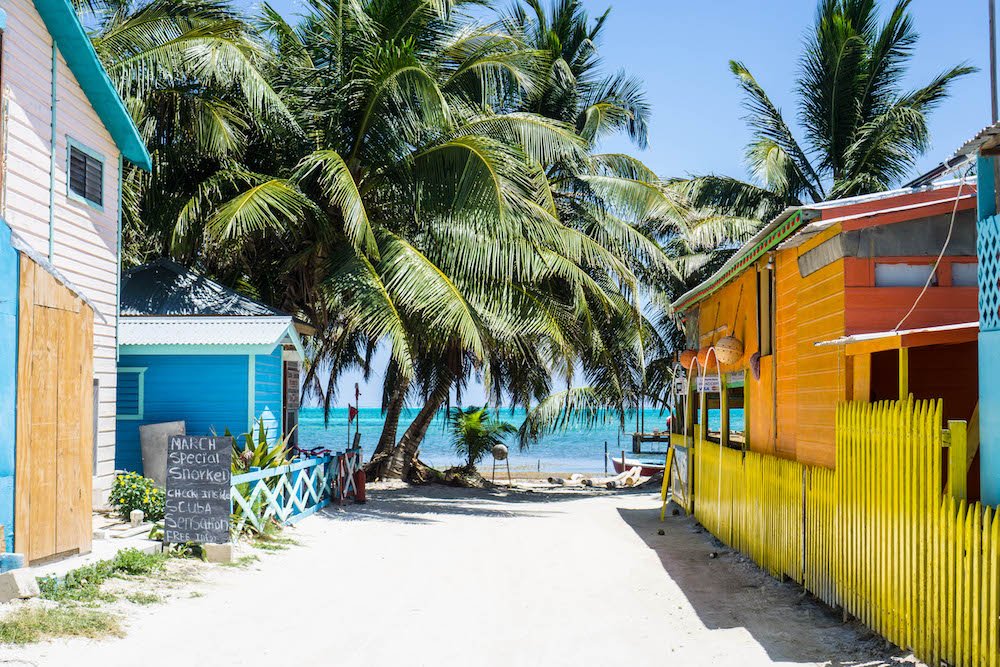 the laid back vibe of houses on the caye caulker sandy streets with orange and blue painted houses