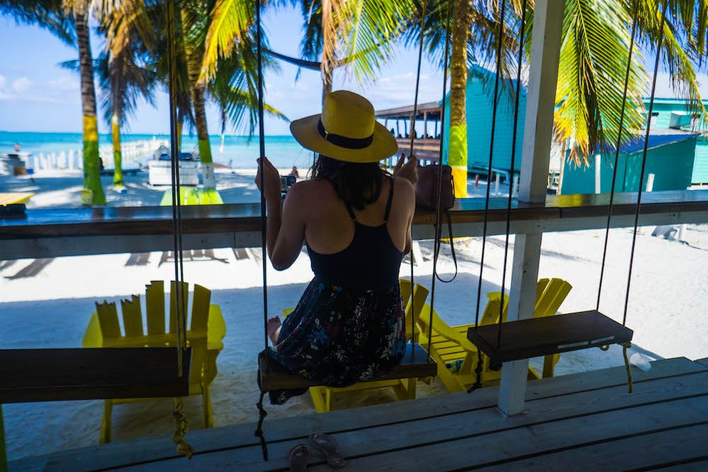 Allison sitting on a swing with a hat and a sundress