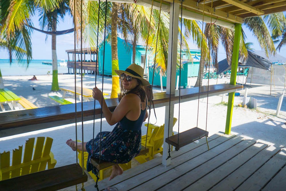 Allison Green sitting on a swing while drinking at a bar in Caye caulker
