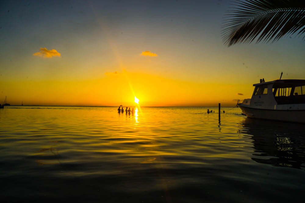 people in the water at sunset on caye caulker