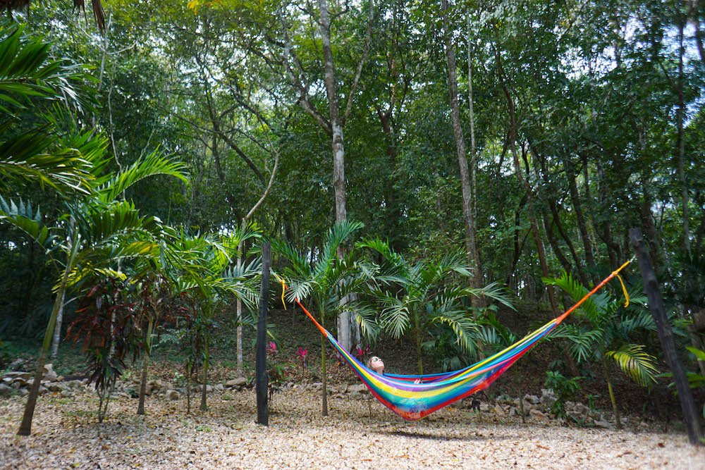 Allison Green in an eco lodge in Belize in a rainbow colored hammock