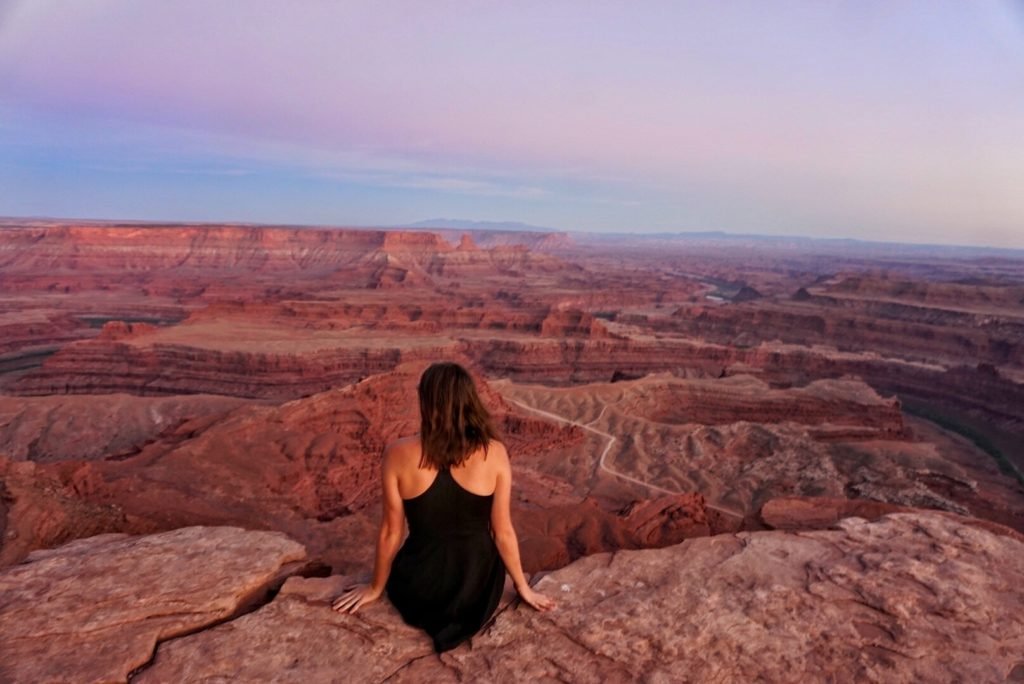 Sitting at the edge of Dead Horse Canyon State Park looking out onto the Colorado RIver and red rocks and sunset colors