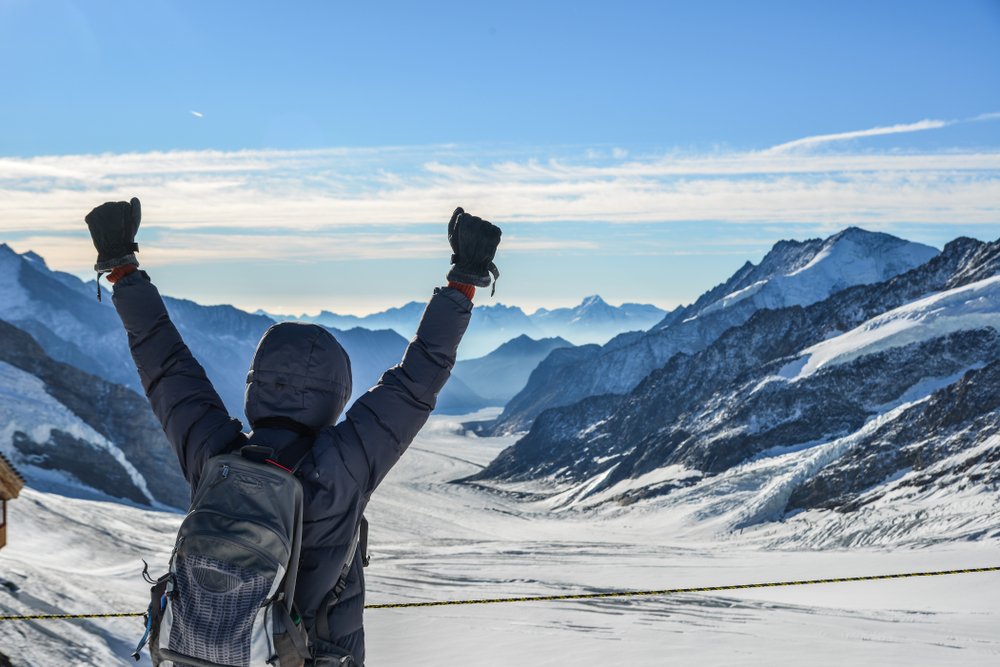 person at the top of jungfraujoch celebrating with their arms in the air