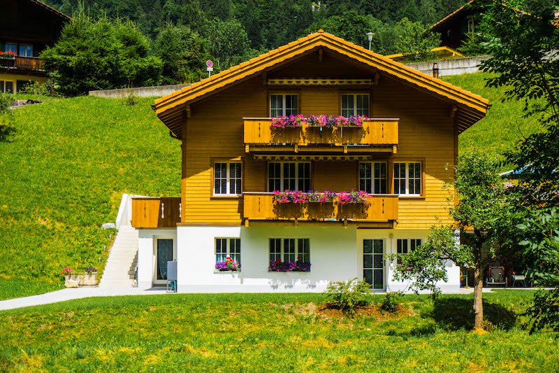 A traditional Swiss wooden chalet style house with colorful flowers in the planterboxes in the small town of Lauterbrunnen, a great day trip from Interlaken