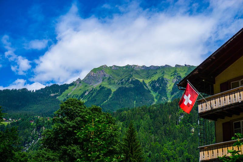 swiss flag on building with mountains in distance