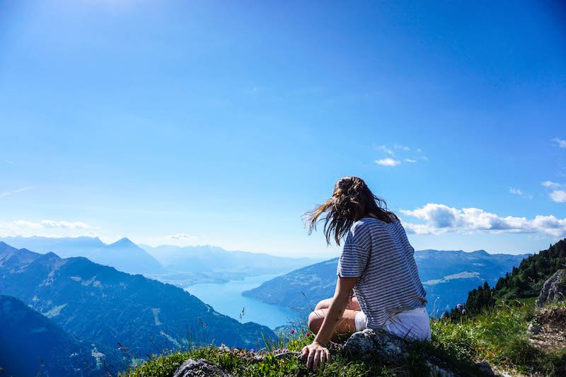 allison atop a mountain at schynigge platte with beautiful views of a lake behind her