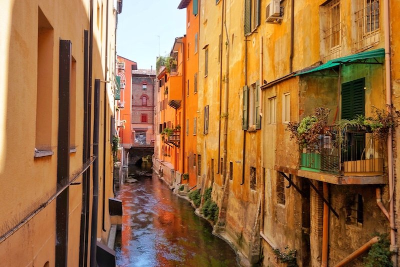 The little venice 'canal' of bologna with red, yellow, and orange buildings and a canal running between them