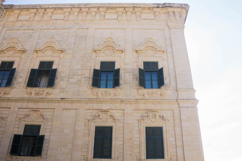 Architectural details on a building in valletta, focusing on the carvings and shutters of the building