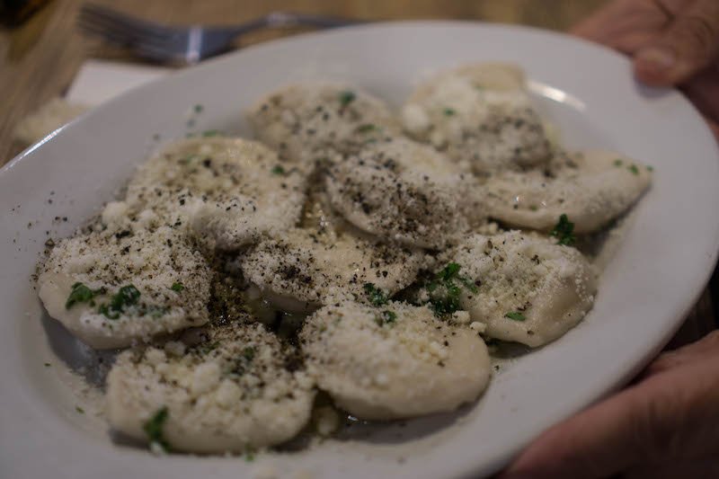 ravioli like dumplings covered in cheese and pepper