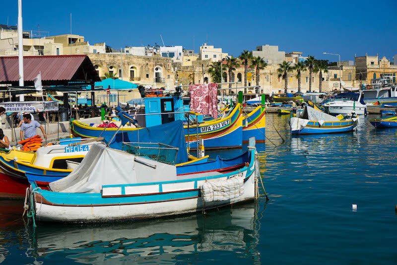 colorful boats on the edge of the harbor in marsaxlokk on a sunny day 