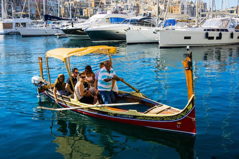 Man steering a traditional colorful boat in Malta