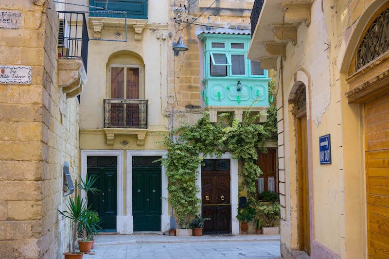 Doors and a colorful bright greenish-blue box balcony in Malta's city of Birgu