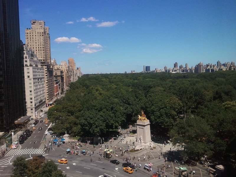 view of central park from columbus circle with lots of trees and building sin the distance.