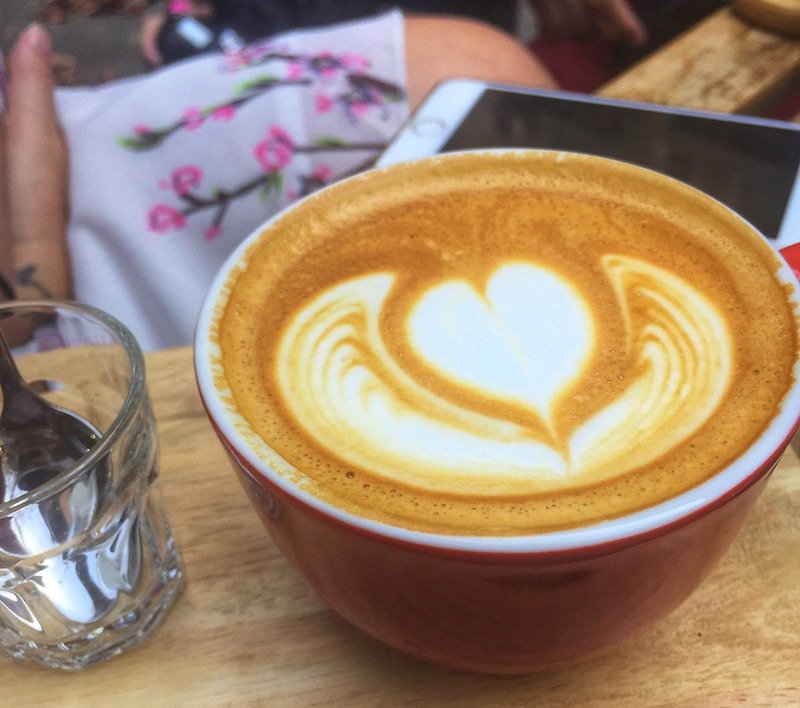 A cup of coffee with some latte art and a phone while in Puerto Rico