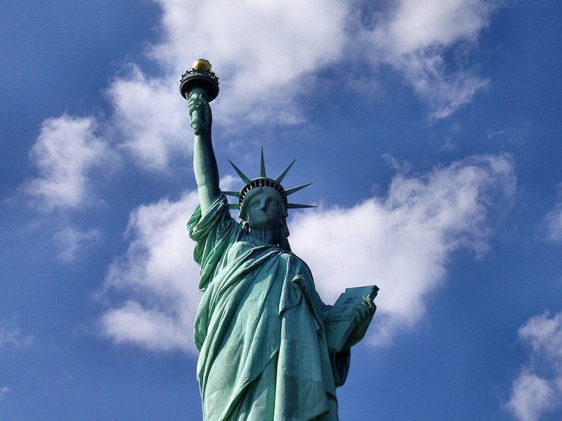 up close view of the statue of liberty holding a torch on a partly cloudy day