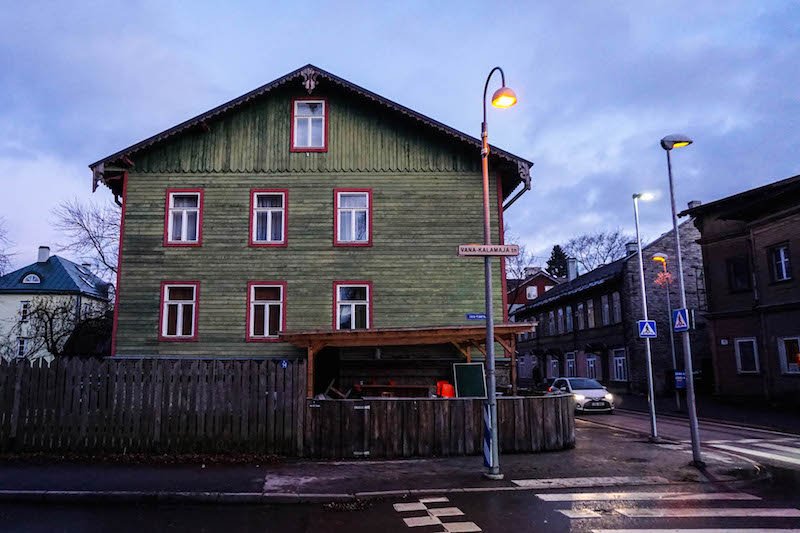 A green house on a street corner in the Kalamaja area of Tallinn in winter at blue hour, when the sun has set yet there is still nice light in the city.