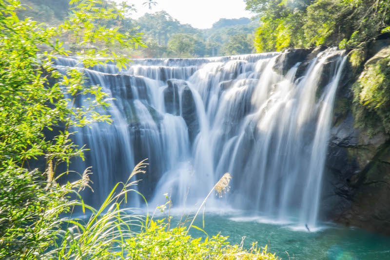 view of shifen waterfall framed by green foliage