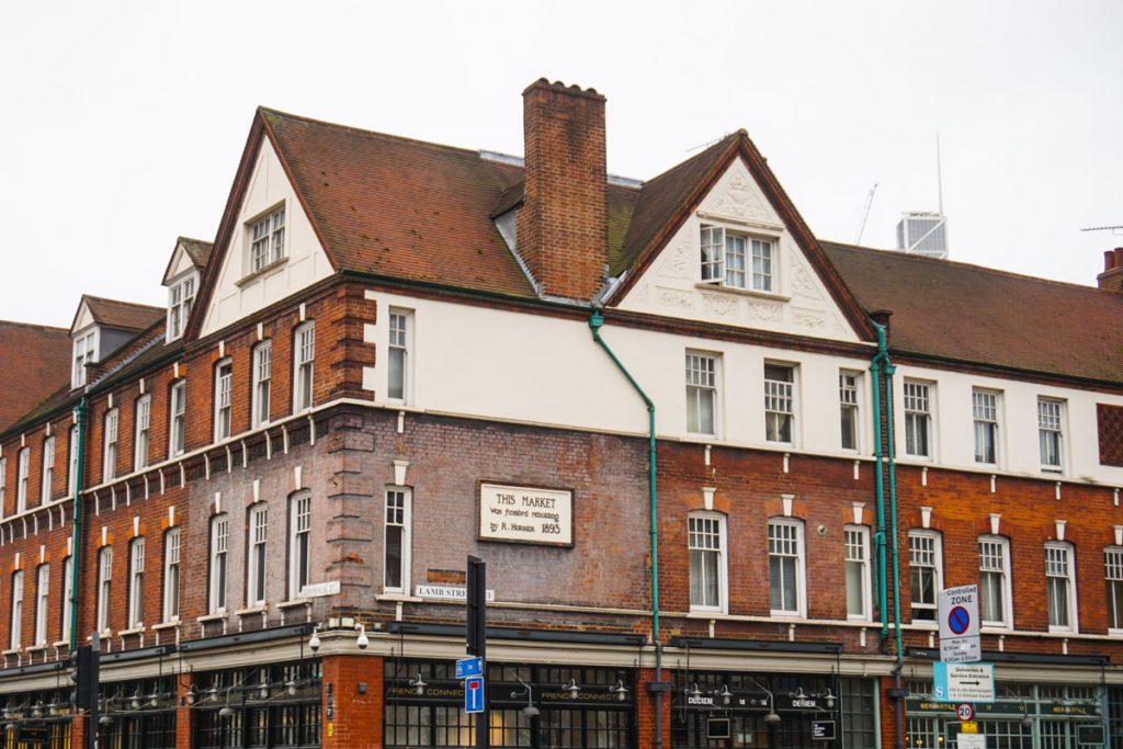 a historic marketplace building with white walls and brick and a historic plaque telling when the market was built