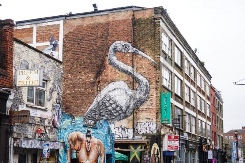 street art of a bird on a brick facade wall in shoreditch london