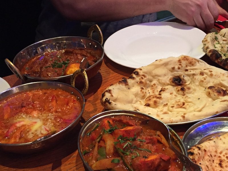 people's hands enjoying indian food in london