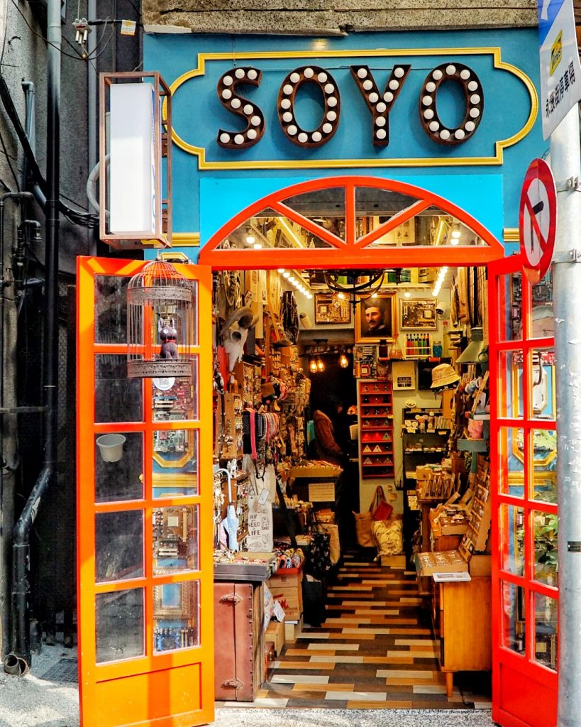 a brightly colored shop with orange door, turquoise paint, with the word SOYO written above it