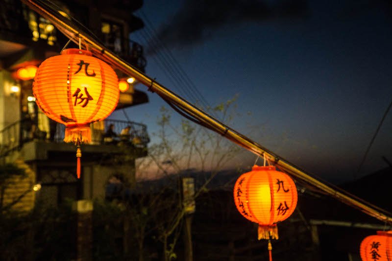 orange lanterns with chinese characters on them with the night sky behind it