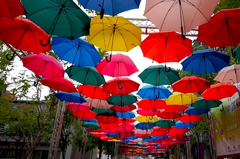 a colorful array of umbrellas hanging above, creating a photogenic alleyway