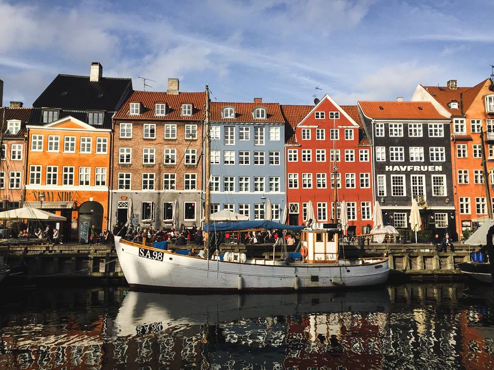 Brilliant colorful houses in red, blue, orange, etc. with a boat in front of the canal in the town center of Nyhavn