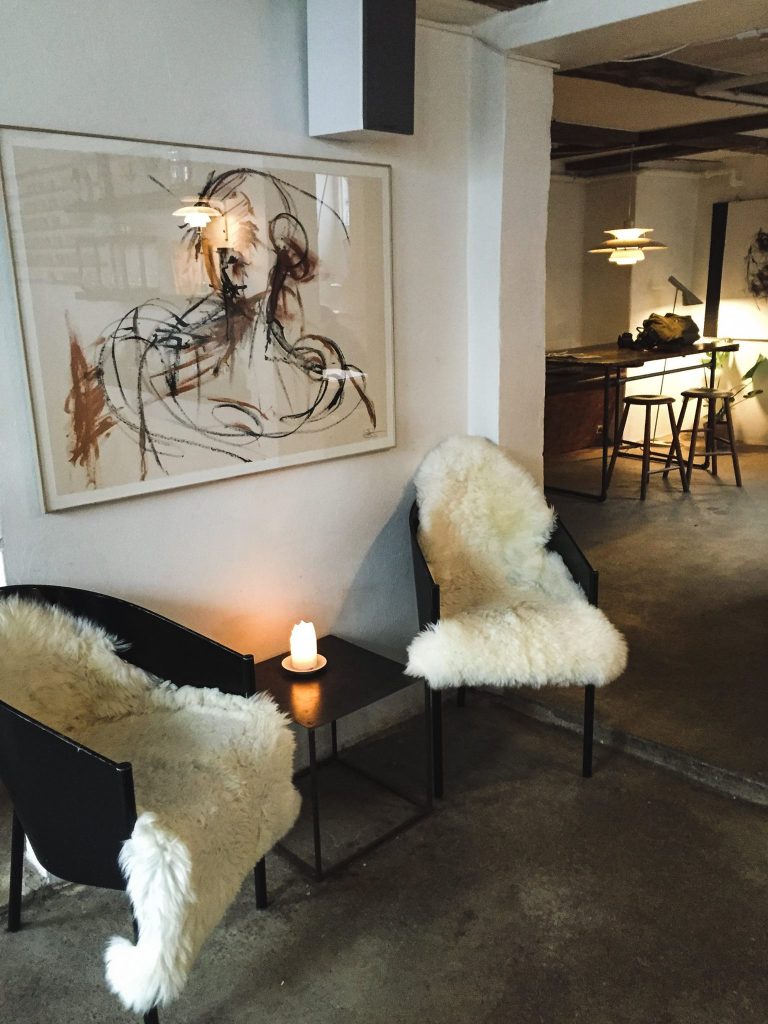 Chic coffee shop in Copenhagen with lush faux-fur throws and paintings in a sleek, Danish design space