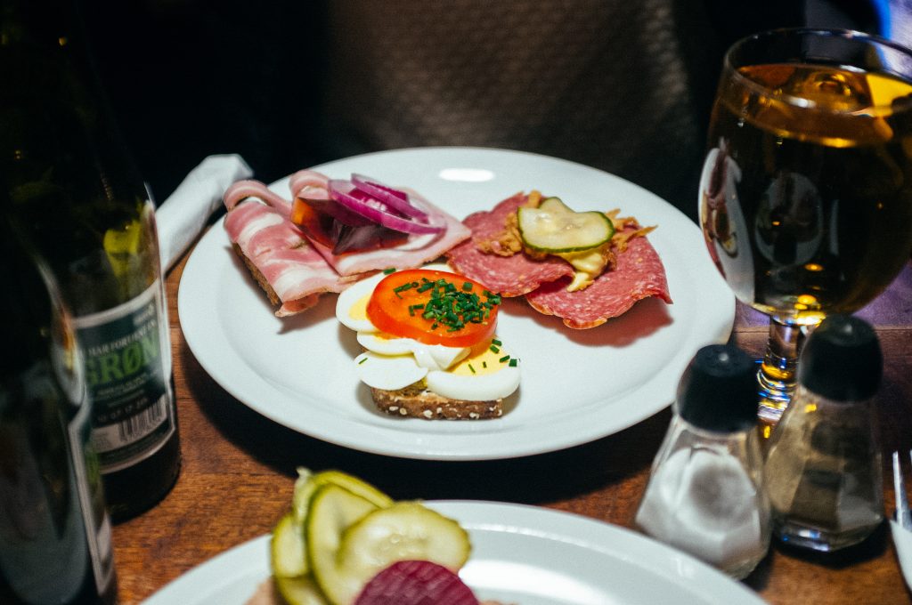 a selection of three danish style smorrebord sandwiches with egg, tomato, ham, pickles, etc.