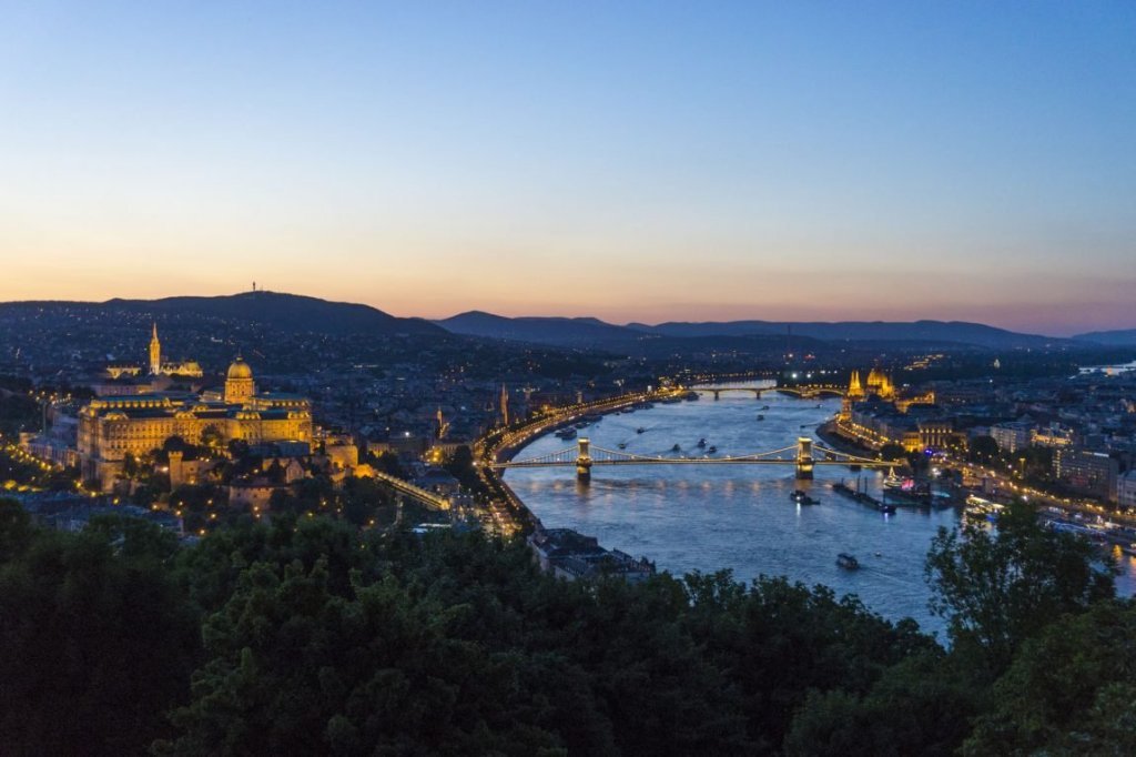 View of the Budapest landscape with the Danube river in the middle with two bridges in the water, view of Buda Castle and the Parliament lit up