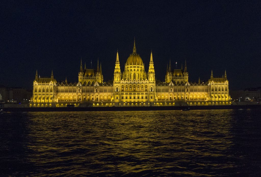 View of the Budapest Parliament at night from a river boat with it all lit up and beautiful in a golden color